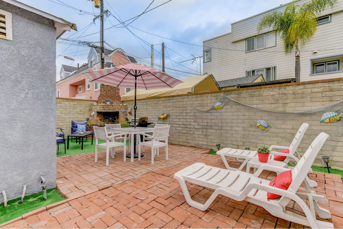 a patio with a table , chairs , umbrella and lounge chairs .