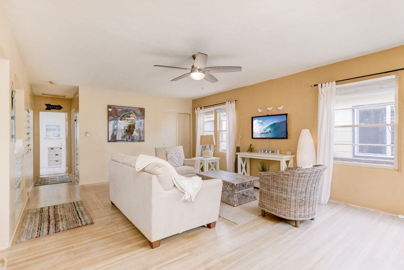 a living room with a white couch , chairs , and a ceiling fan .