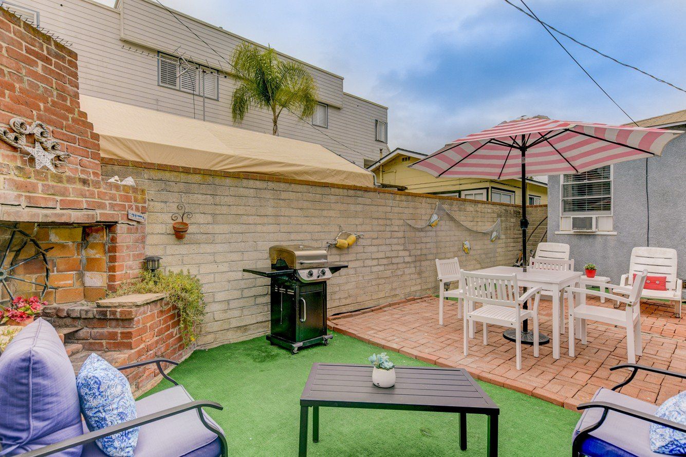 a backyard with a table , chairs , umbrellas and a grill .