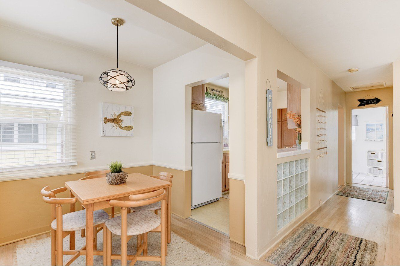 A dining room with a table and chairs and a refrigerator.