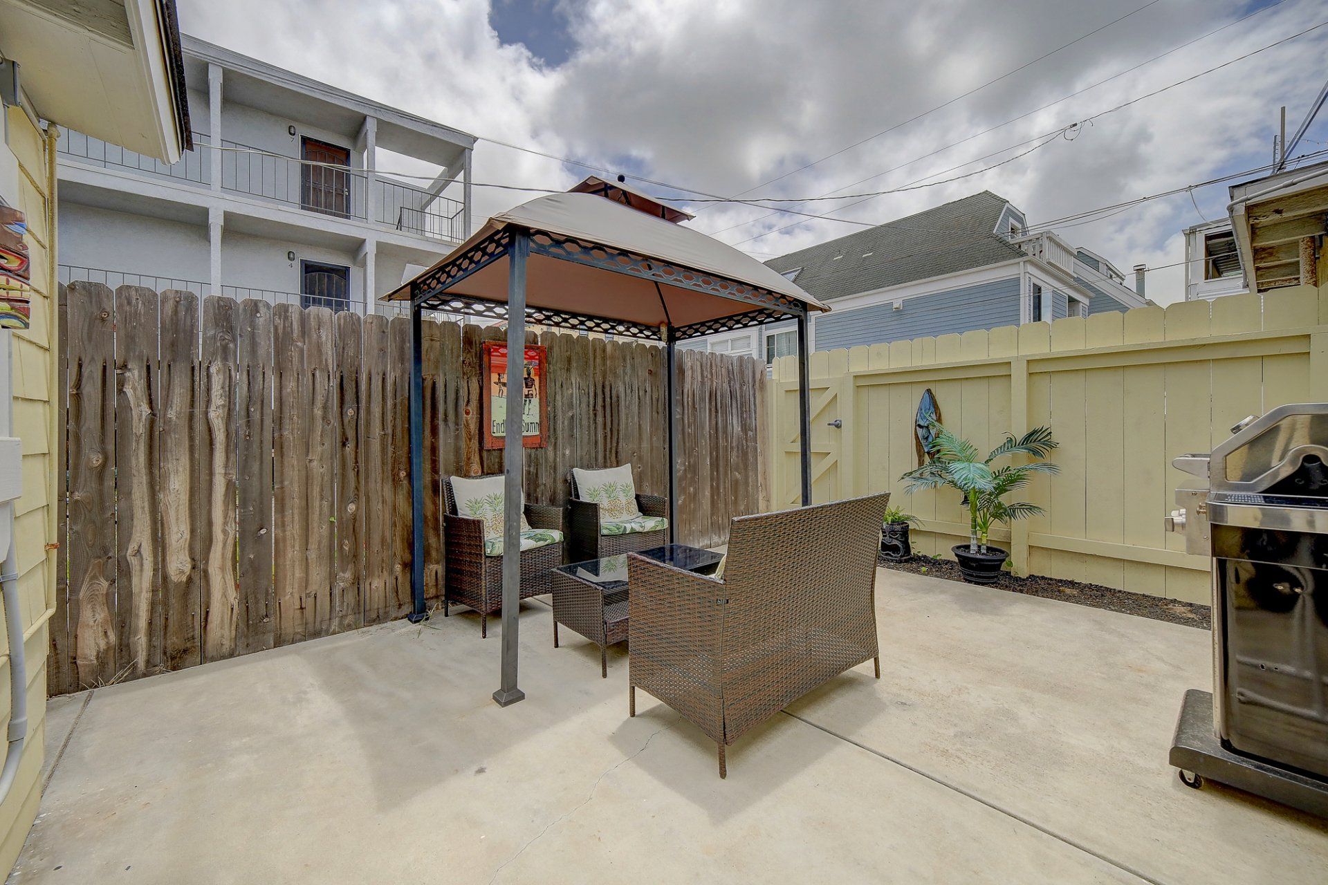 a patio with a gazebo , chairs , and a grill .