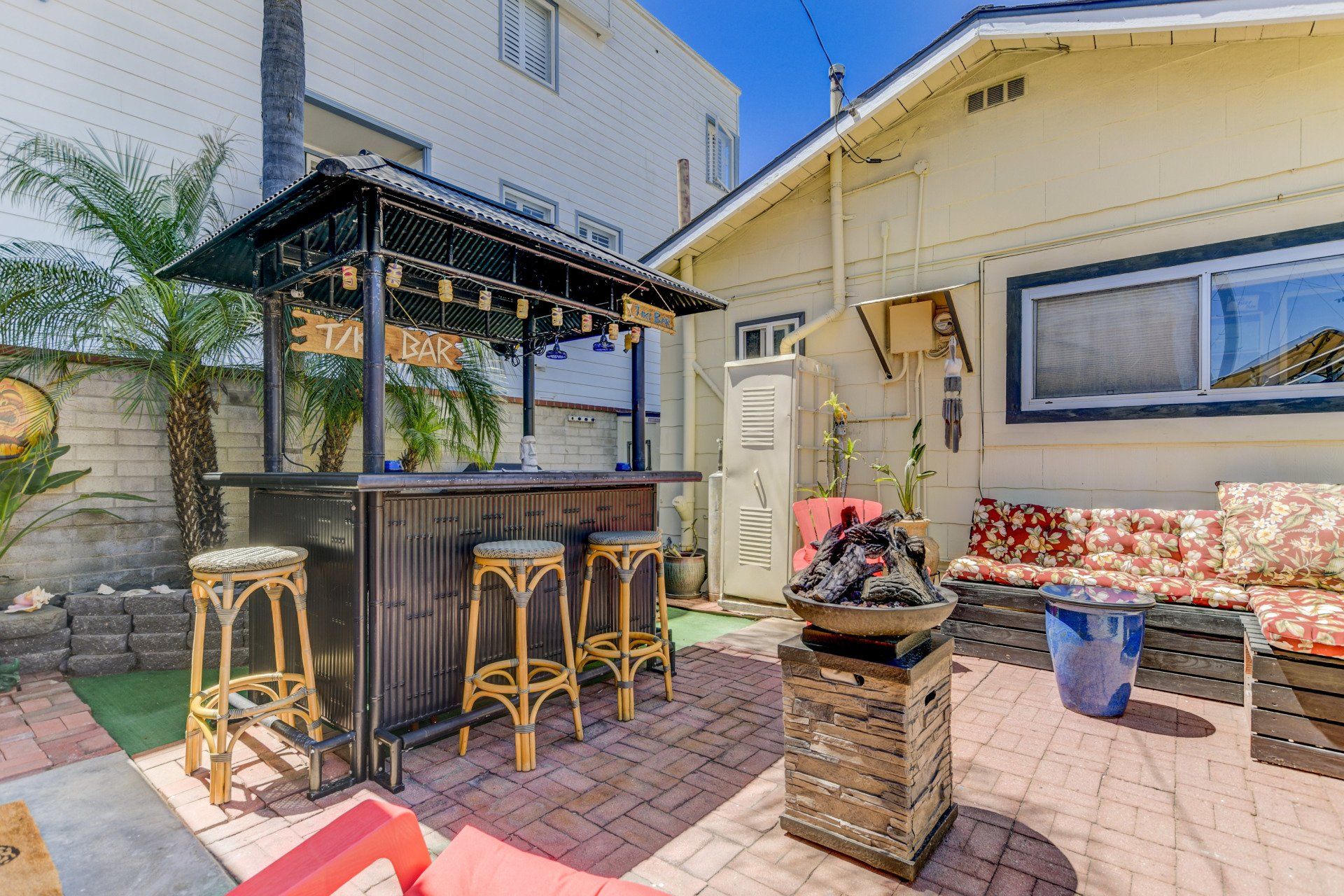 a backyard with a bar and stools in front of a house .