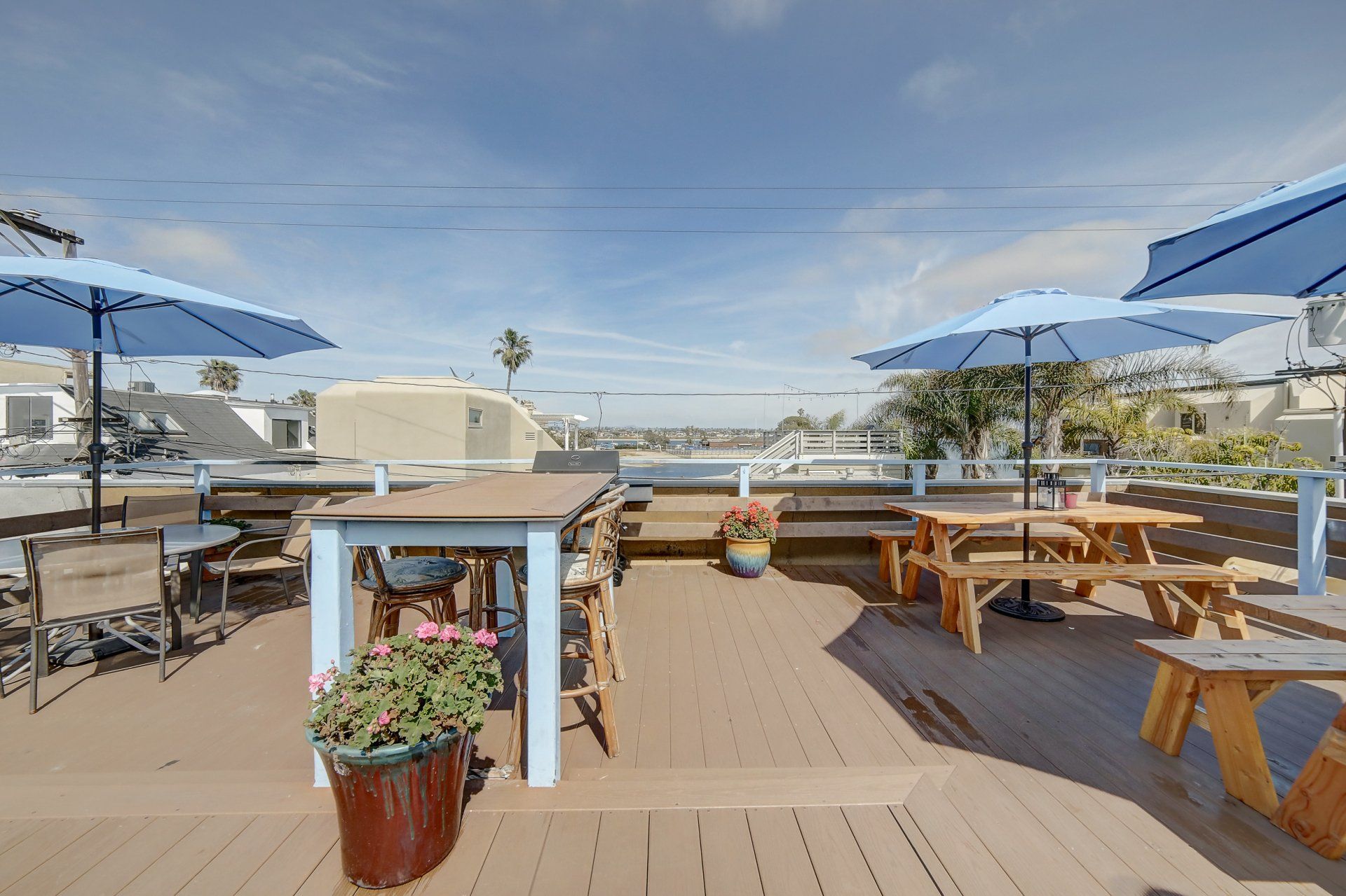 a wooden deck with picnic tables and umbrellas on a sunny day .