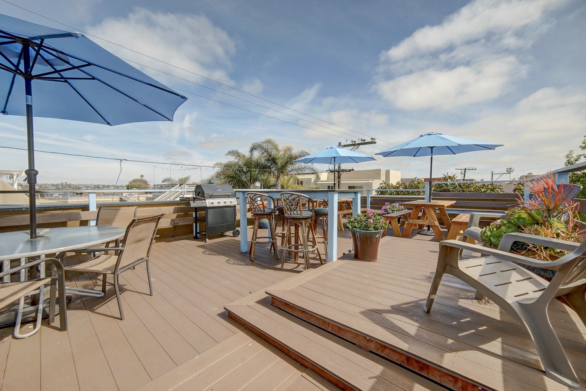 a rooftop deck with tables and chairs and umbrellas