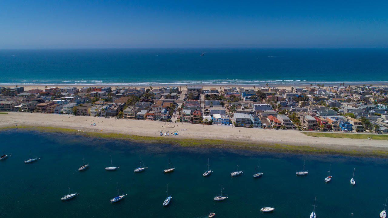 an aerial view of a beach with boats in the water and a city in the background .
