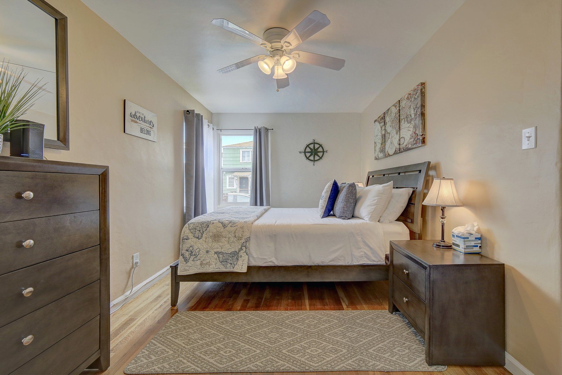 A bedroom with a bed , nightstand , dresser , mirror and ceiling fan.