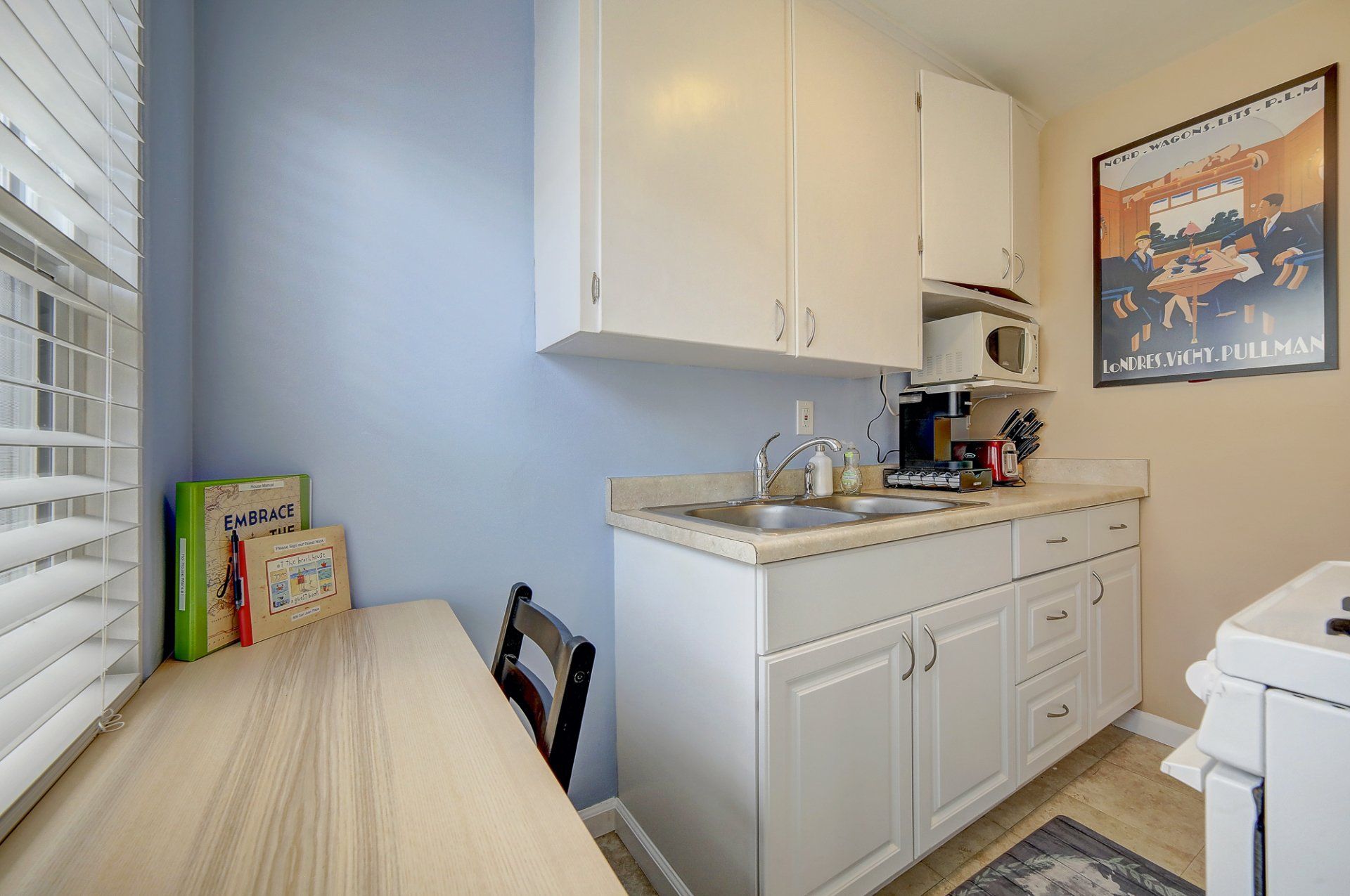 a kitchen with white cabinets , a sink , a microwave and a table .