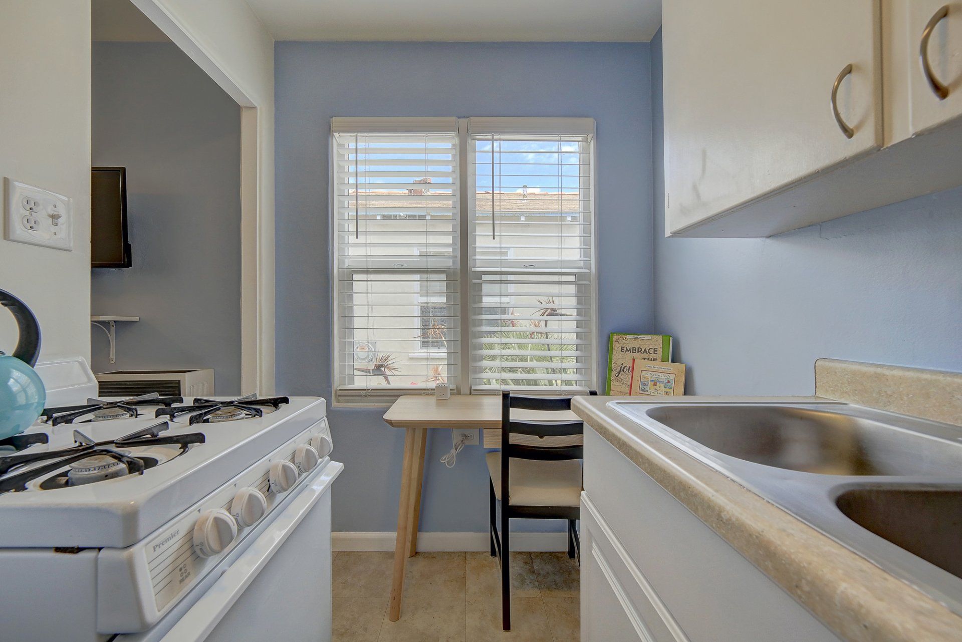 a kitchen with a stove , sink , chair and window .