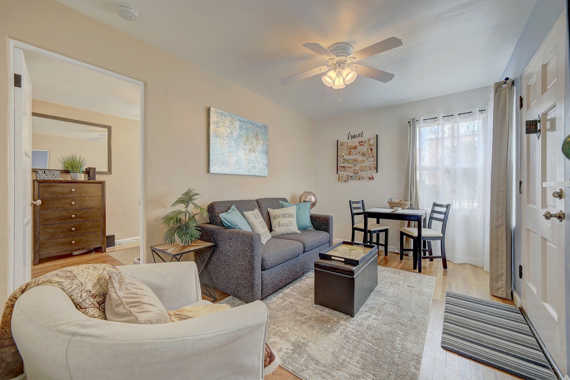 a living room with a couch , chair , table and ceiling fan .