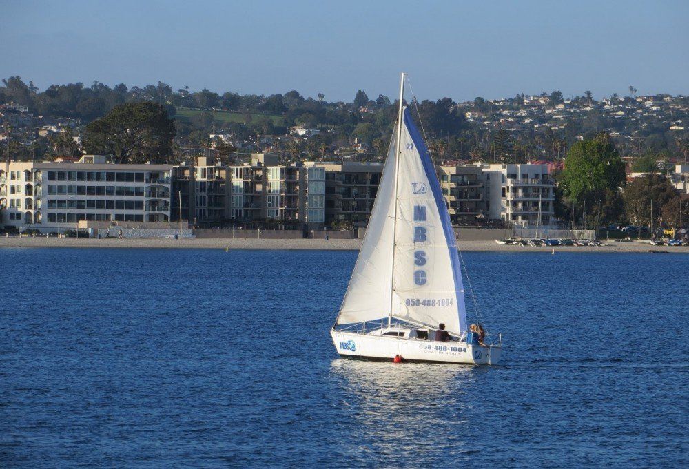 a sailboat is floating on a body of water with buildings in the background .