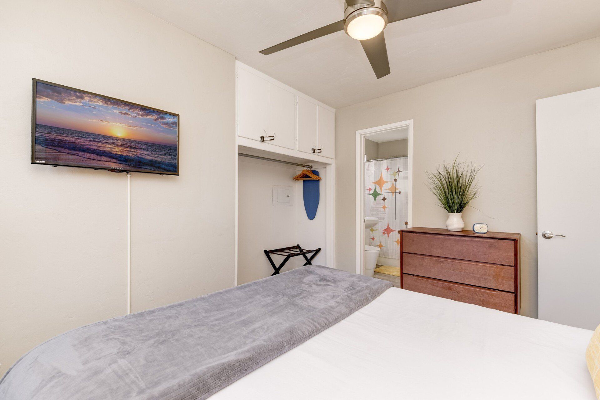 a bedroom with a bed , dresser , television and ceiling fan .