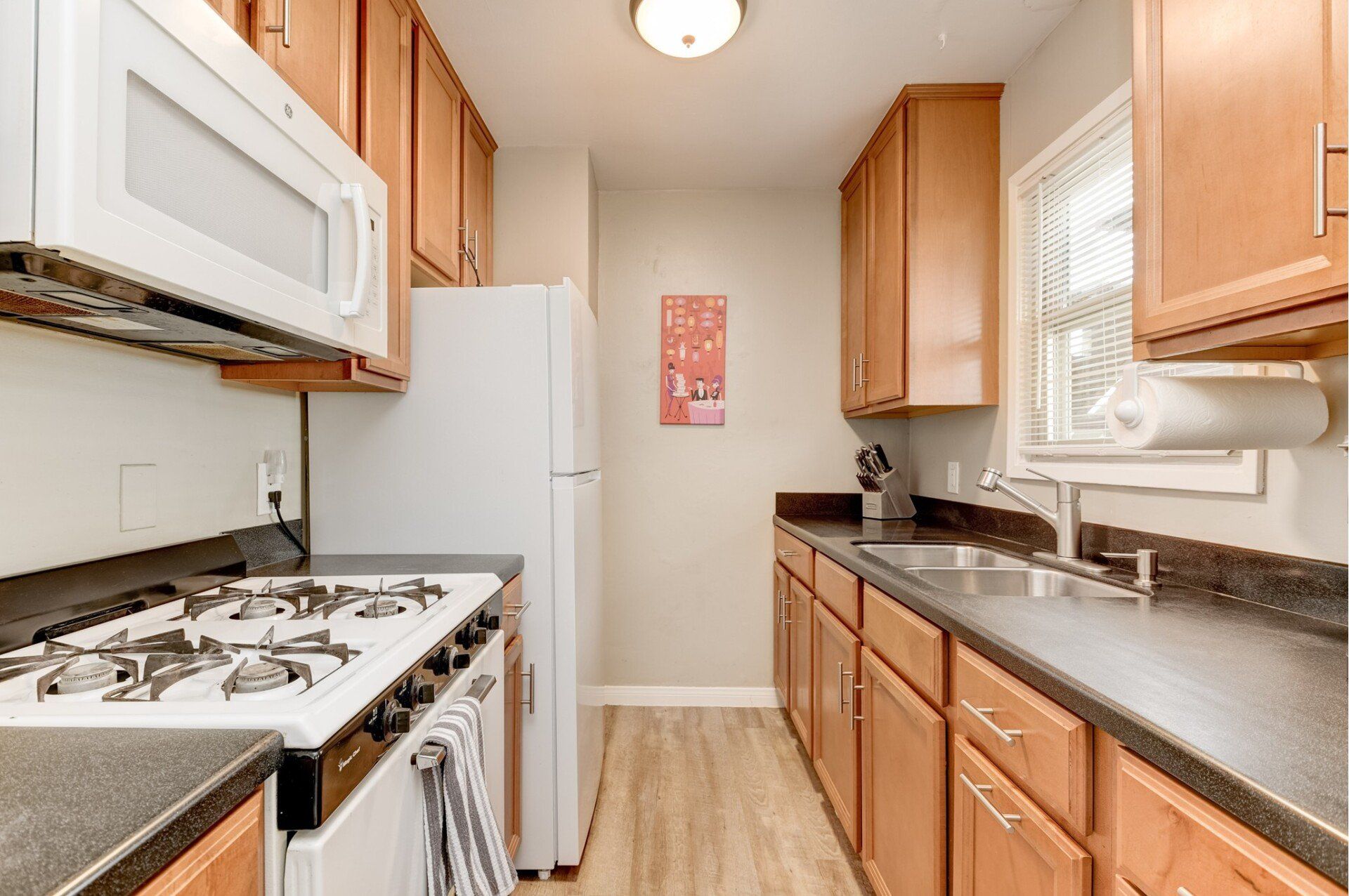 a kitchen with a stove , refrigerator , microwave and sink