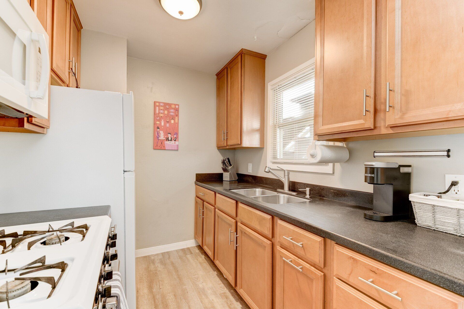 a kitchen with wooden cabinets , a refrigerator , stove , sink and microwave .