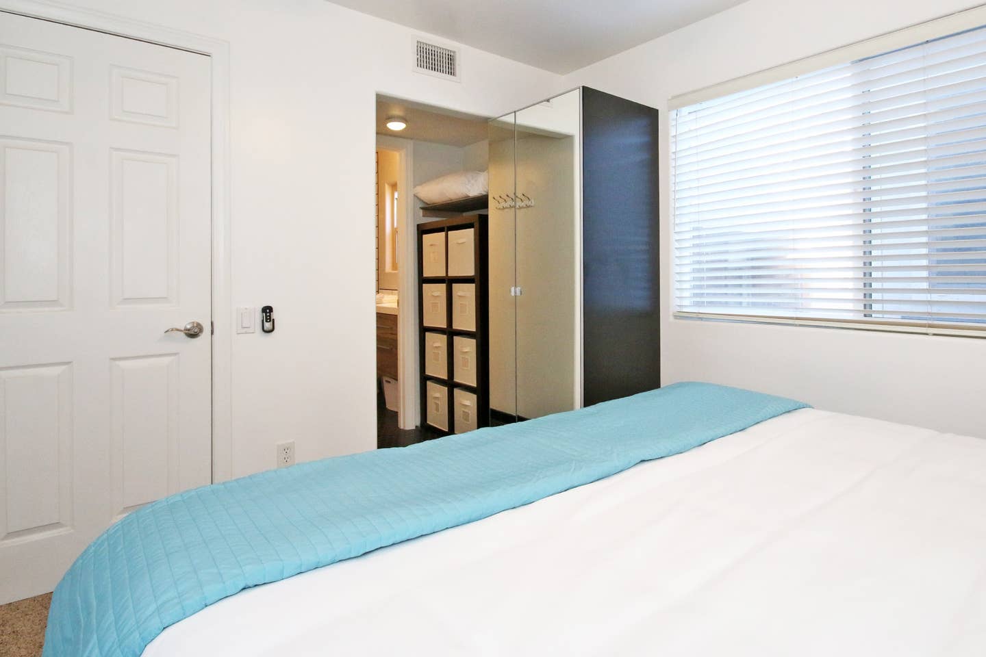 A bedroom with a bed and a window with blinds