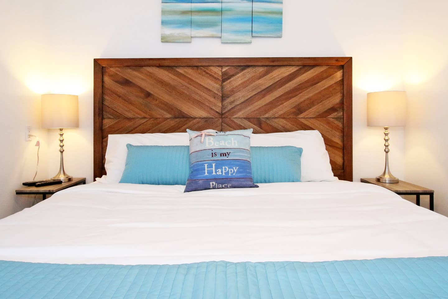 A bed with a wooden headboard and a blue pillow that says happy