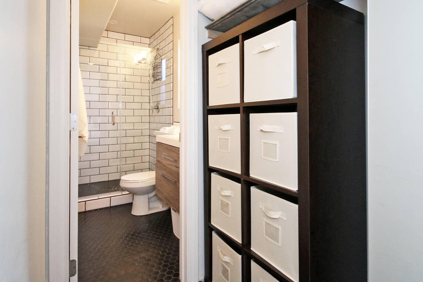 A bathroom with a toilet and a shelf with drawers