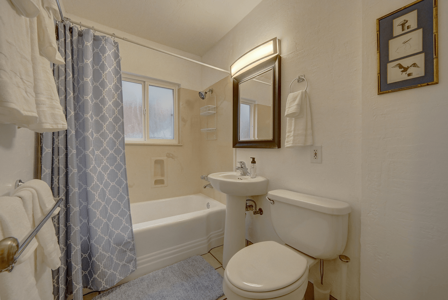 A bathroom with a toilet , sink , bathtub and mirror.