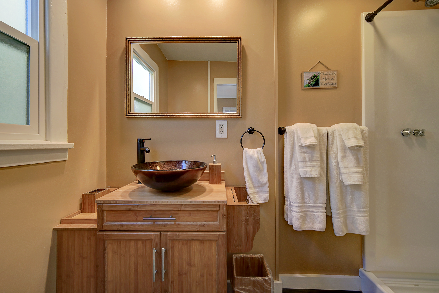 a bathroom with a sink , mirror , and towels hanging on the wall .