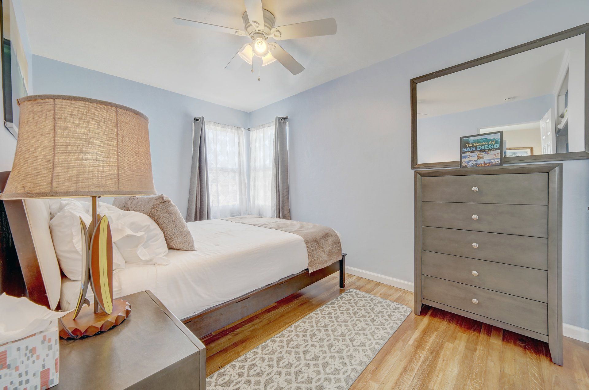 a bedroom with a bed , dresser , lamp and mirror .