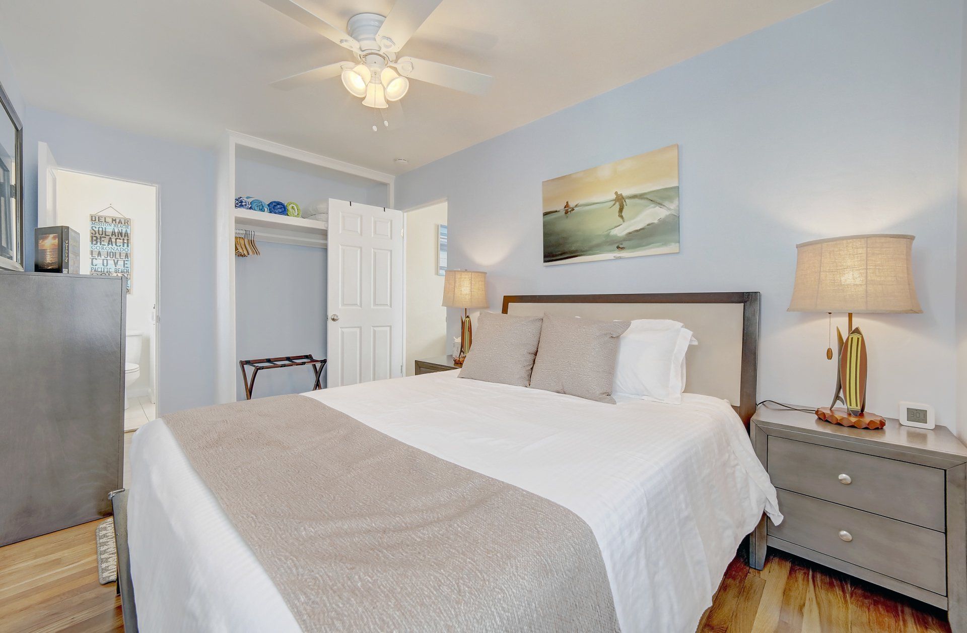 a bedroom with a king size bed , nightstand , lamps and a ceiling fan .