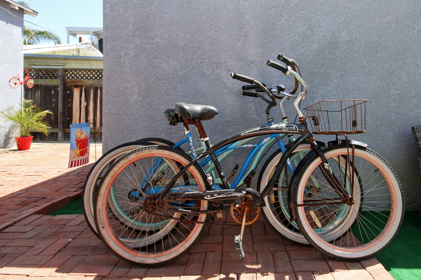 three bicycles are stacked on top of each other on a brick sidewalk .