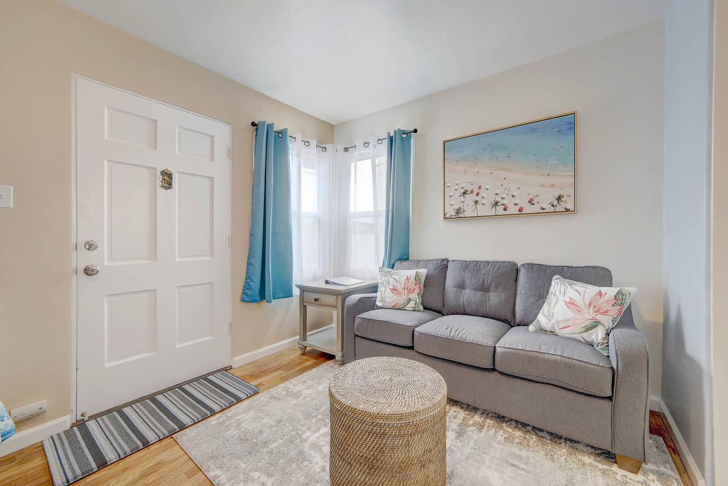 A living room with a couch , table , rug and a painting on the wall.