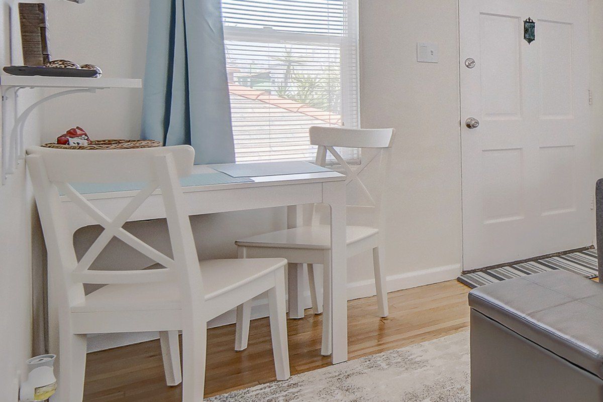 A living room with a table and chairs in front of a window.