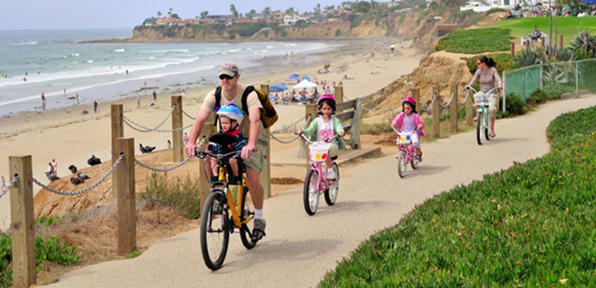 a group of people are riding bikes on a path near the beach .