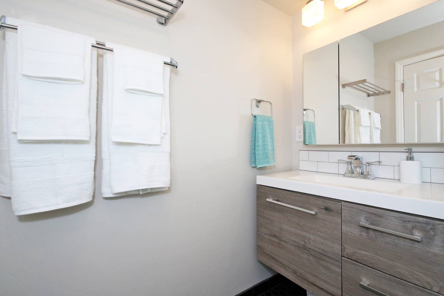 A bathroom with a sink , mirror , and towels hanging on the wall.