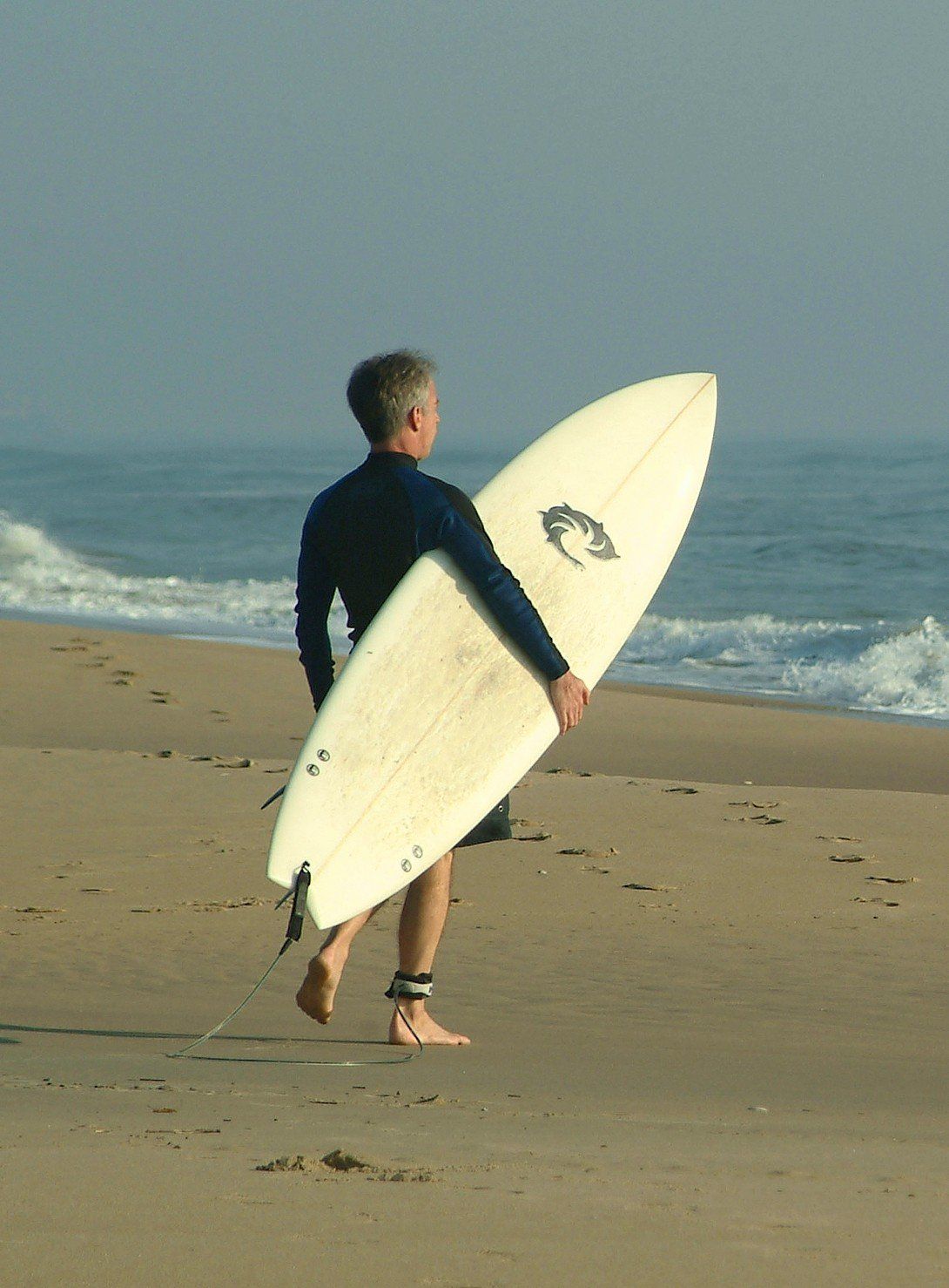 a man carrying a surfboard with the letter c on it