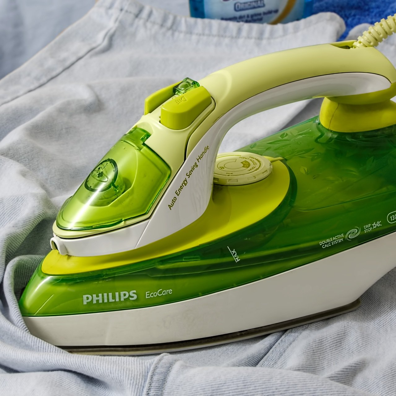 a green and white philips iron is sitting on a shirt