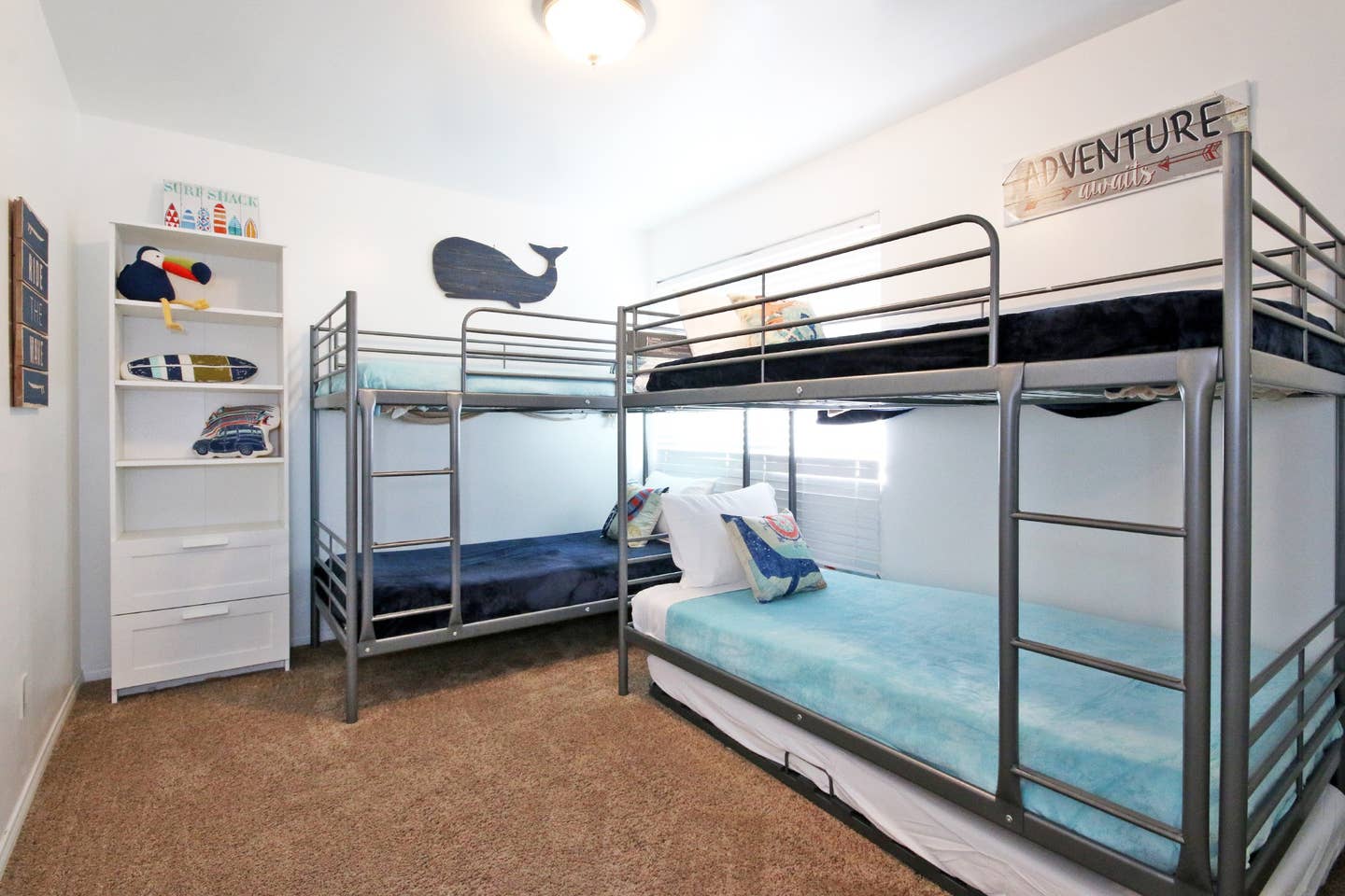 A bedroom with three bunk beds and a whale on the wall.