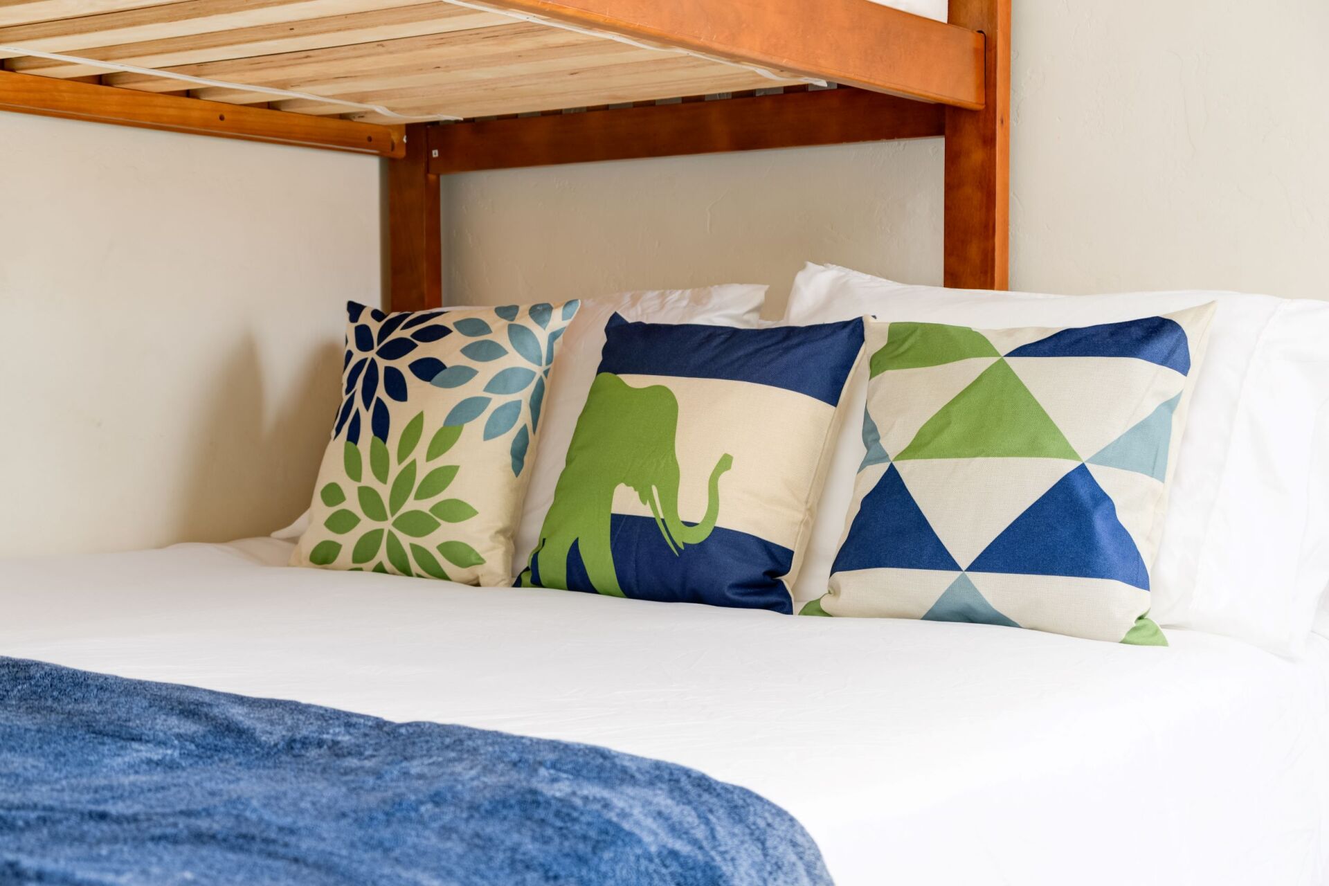 A bunk bed with blue and green pillows on it