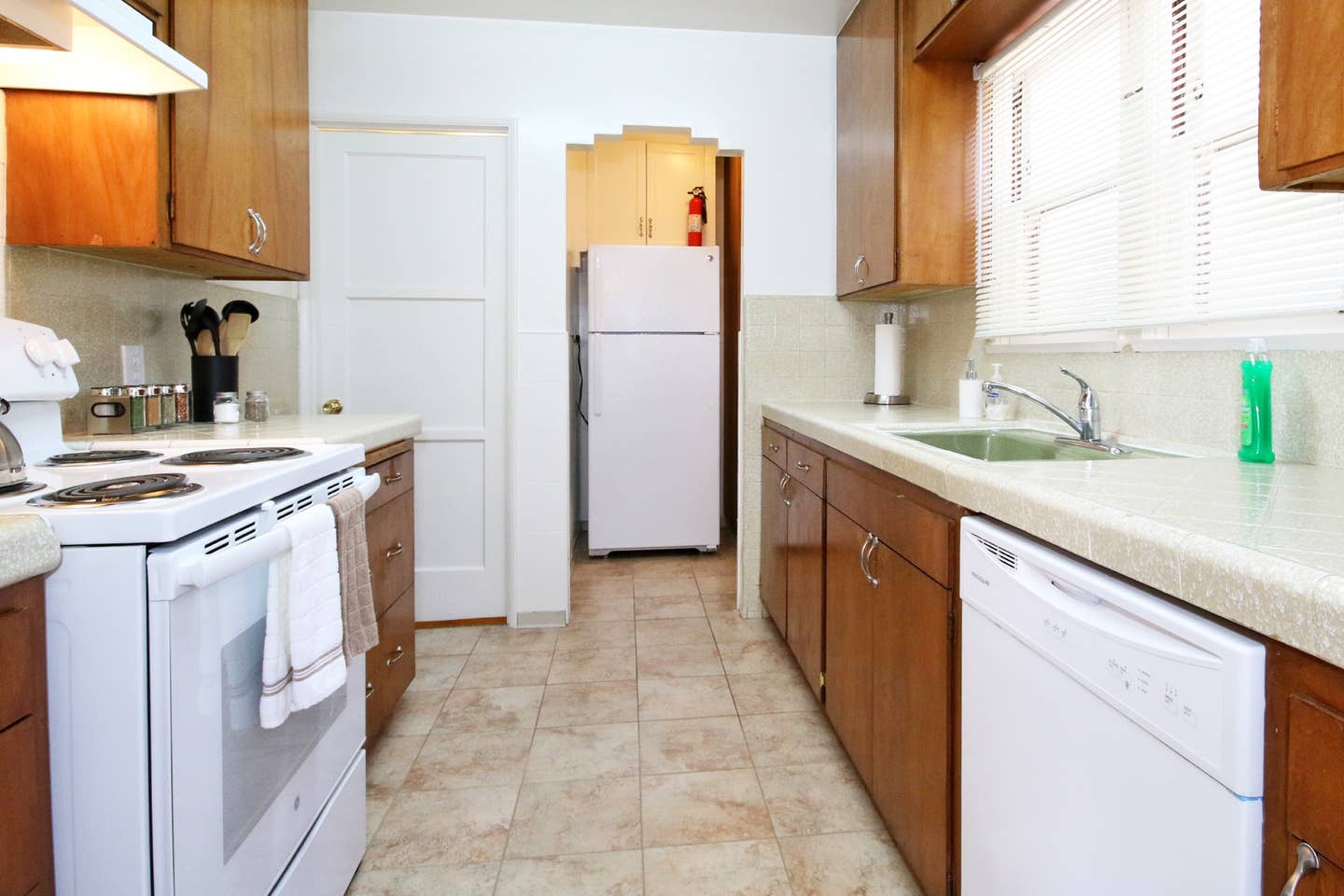 A kitchen with a stove , refrigerator , sink and dishwasher