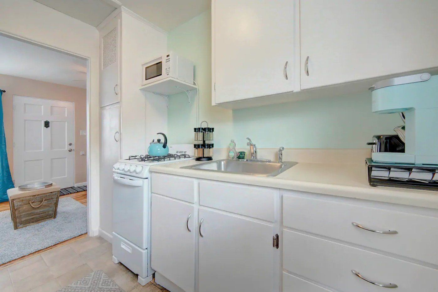 a kitchen with white cabinets , a stove , a sink , and a microwave .