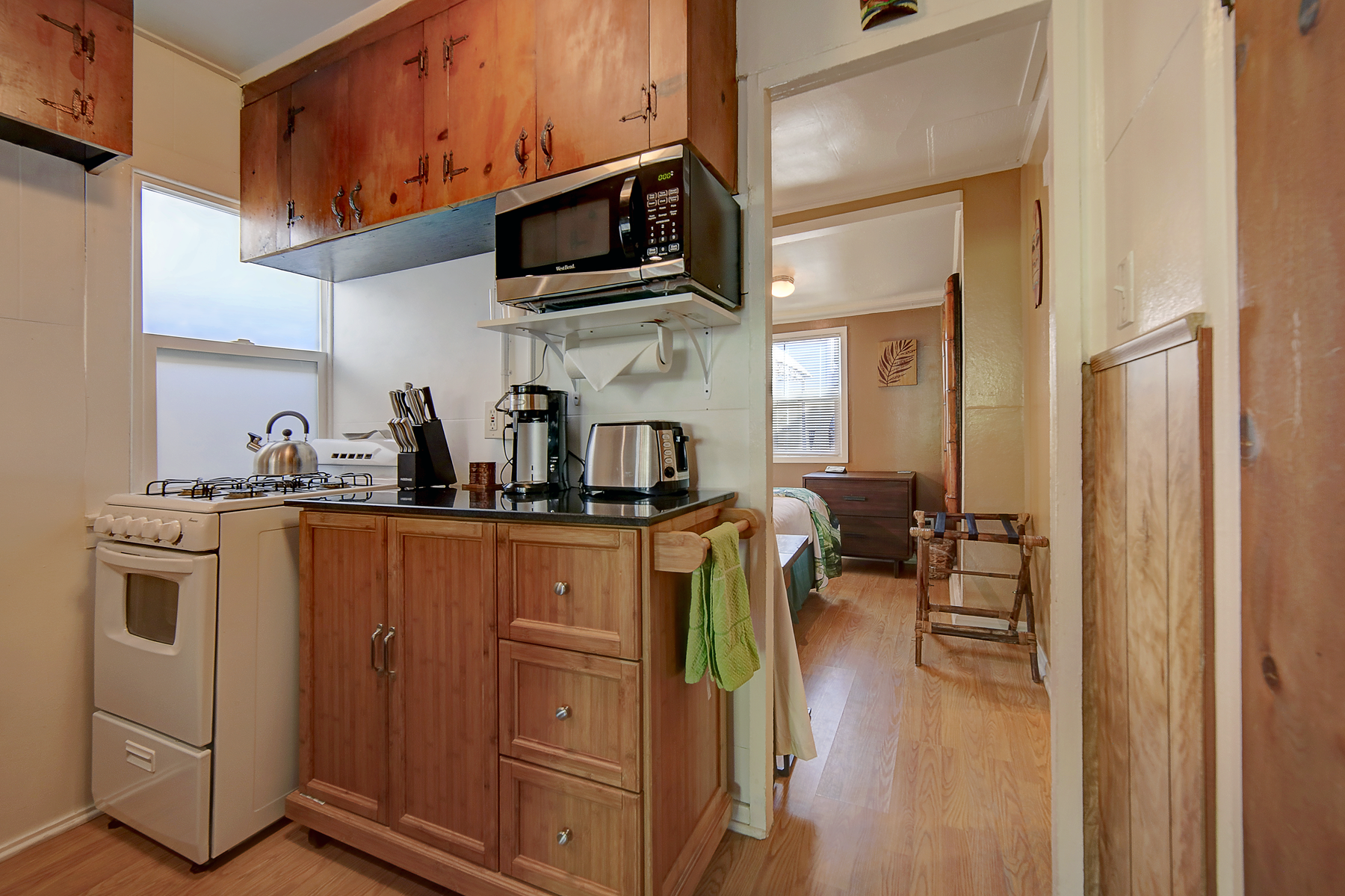 a kitchen with wooden cabinets , a stove , a microwave , and a coffee maker .