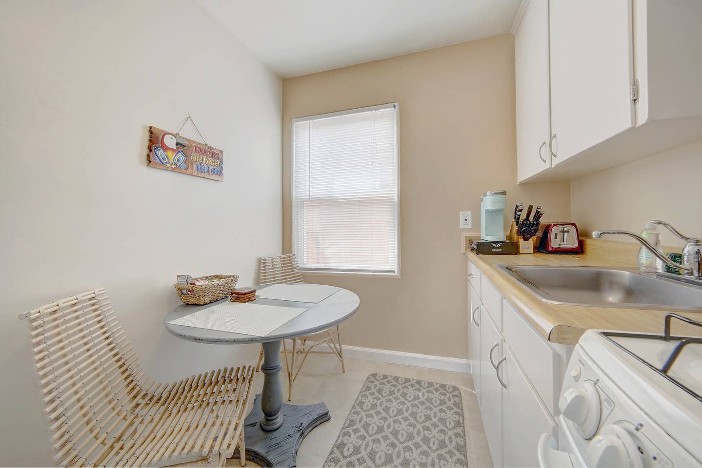 A kitchen with a table , chairs , sink and stove.