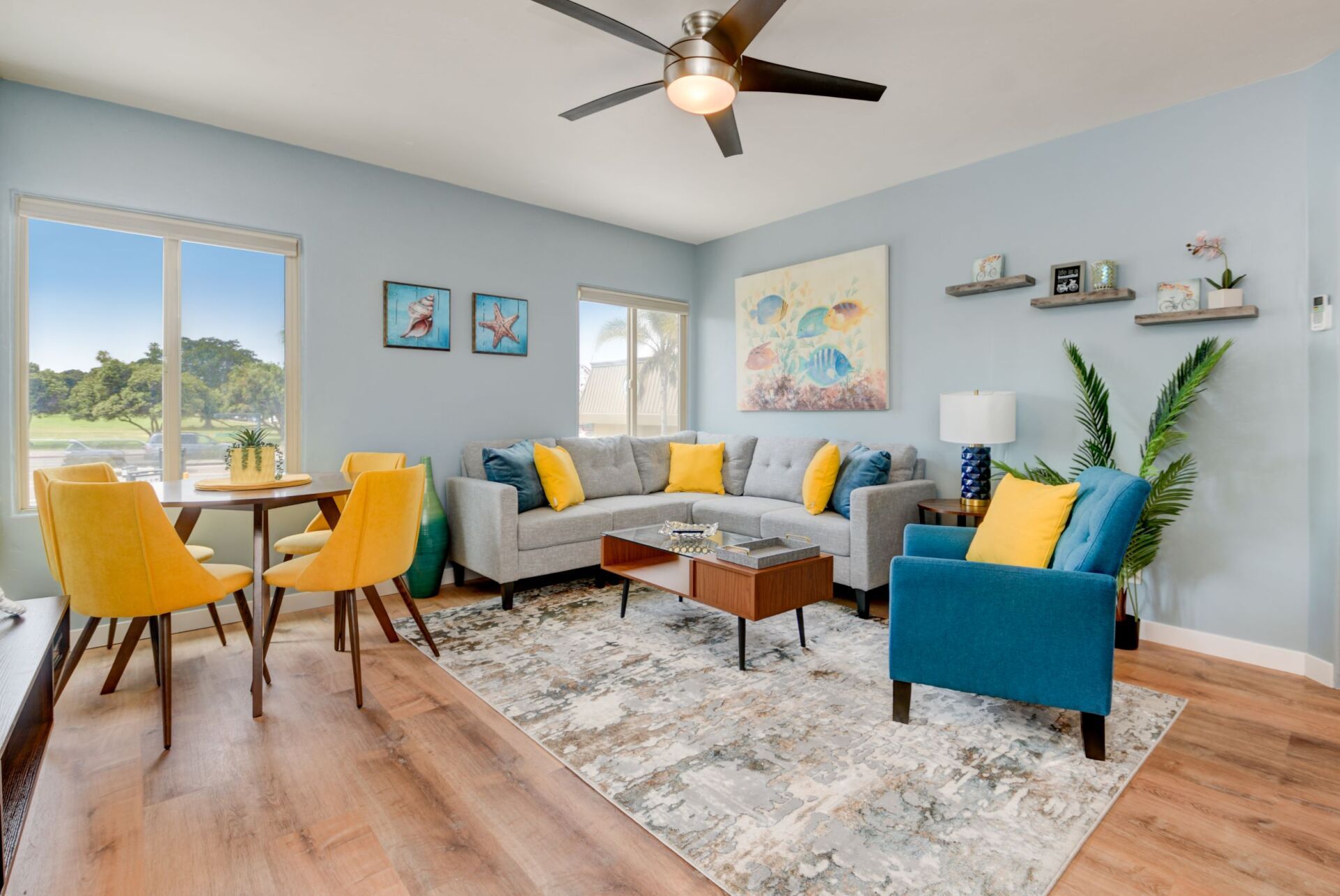 A living room with a couch , chairs , a table and a ceiling fan.