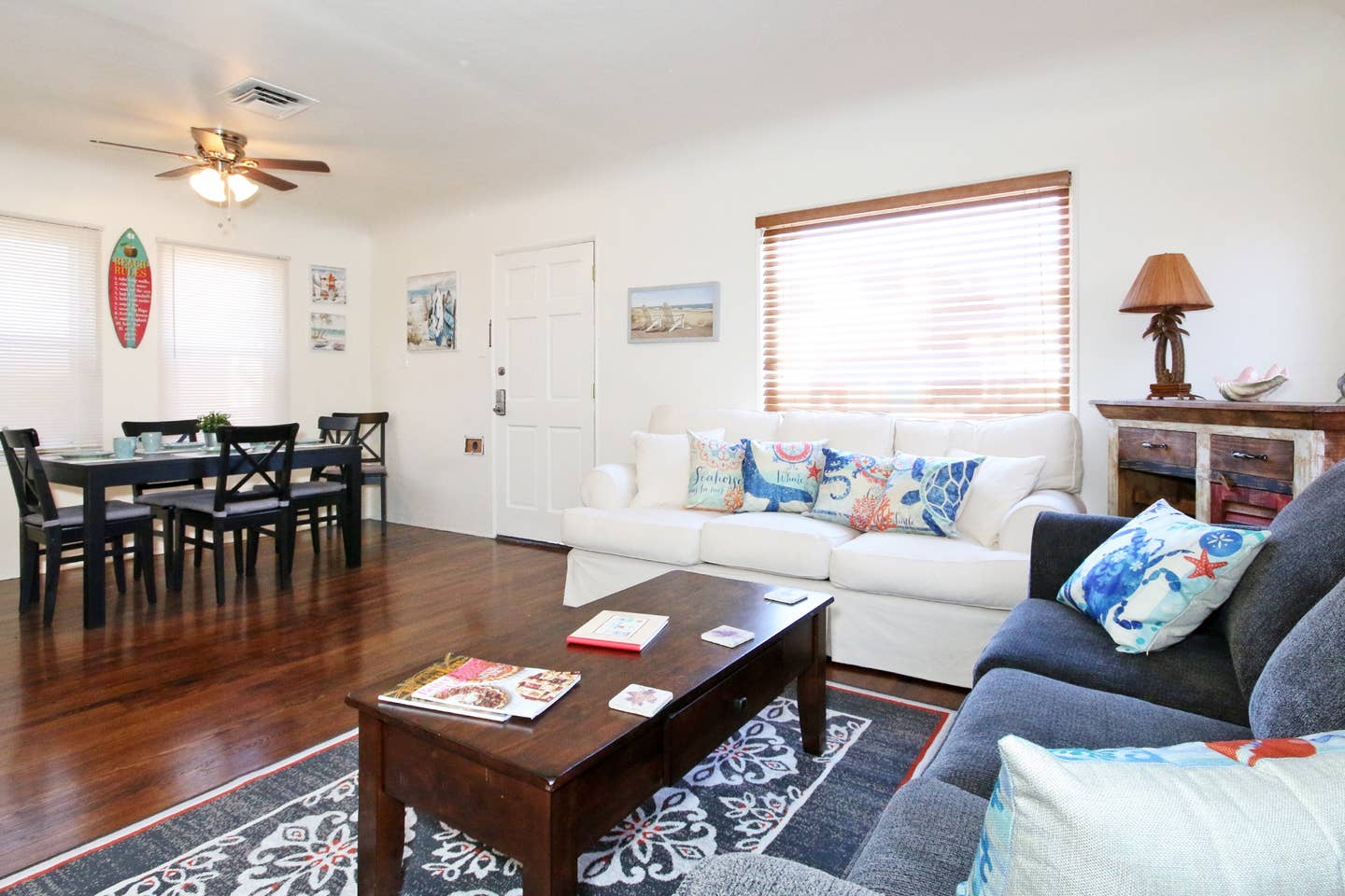 A living room with a couch , table , chairs and a ceiling fan.