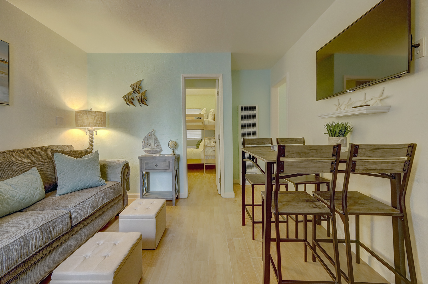 A living room with a couch , table and chairs and a flat screen tv.