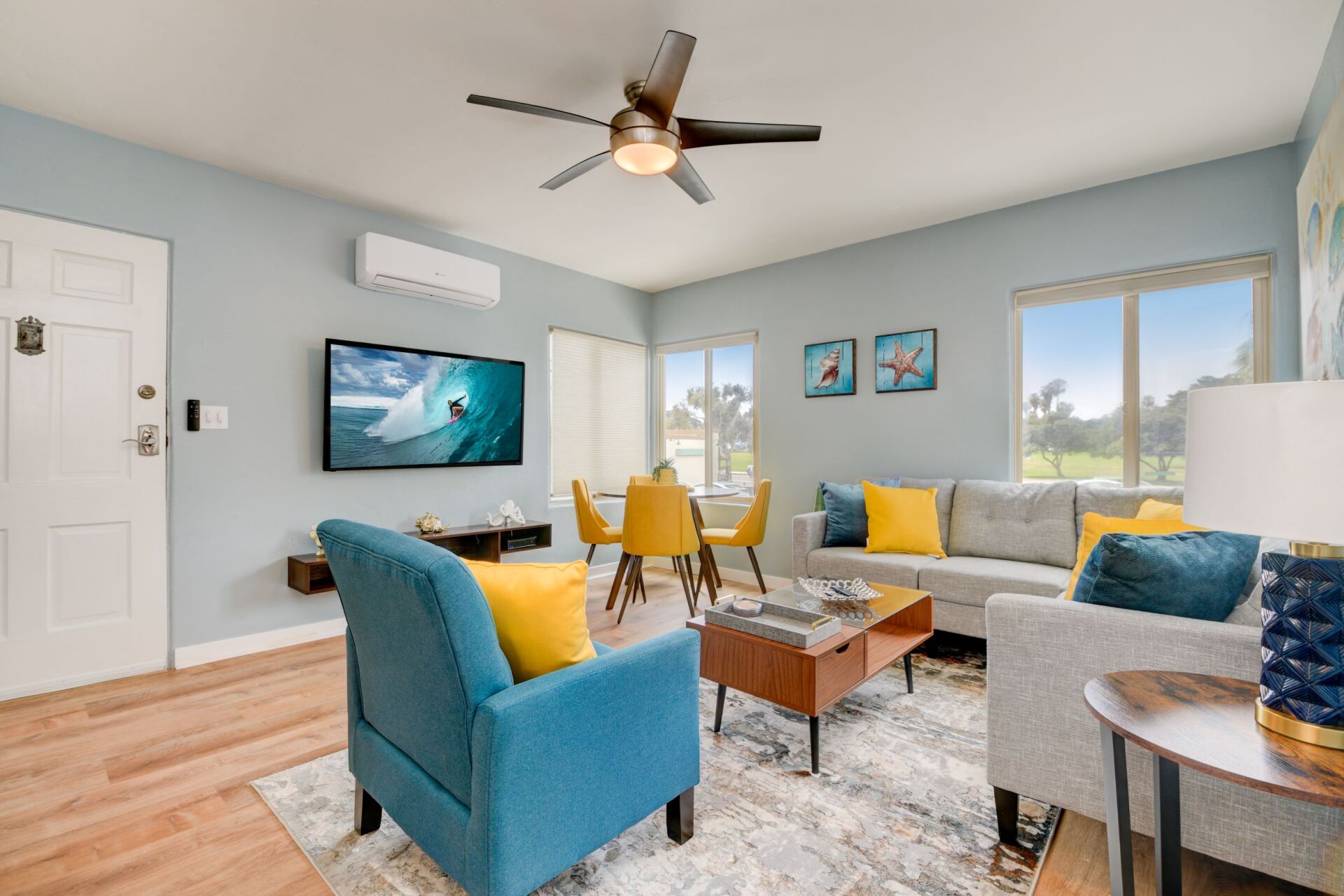 A living room with a couch , chairs , coffee table and television.