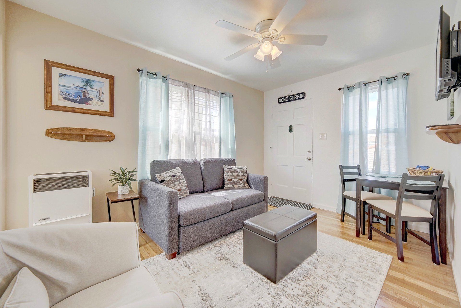 A living room with a couch , table , chairs and a ceiling fan.