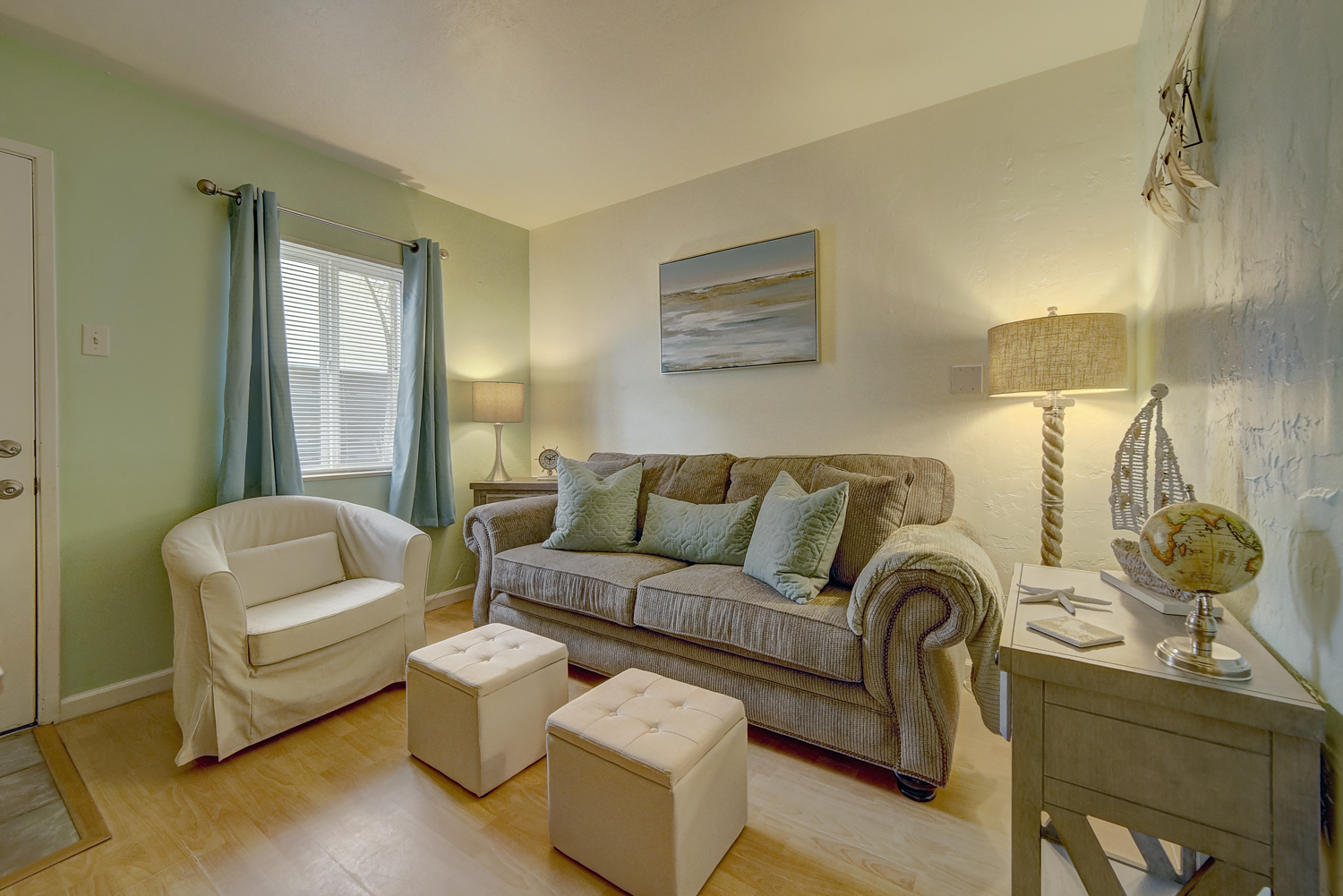 A living room with a couch , chair , ottoman and table.