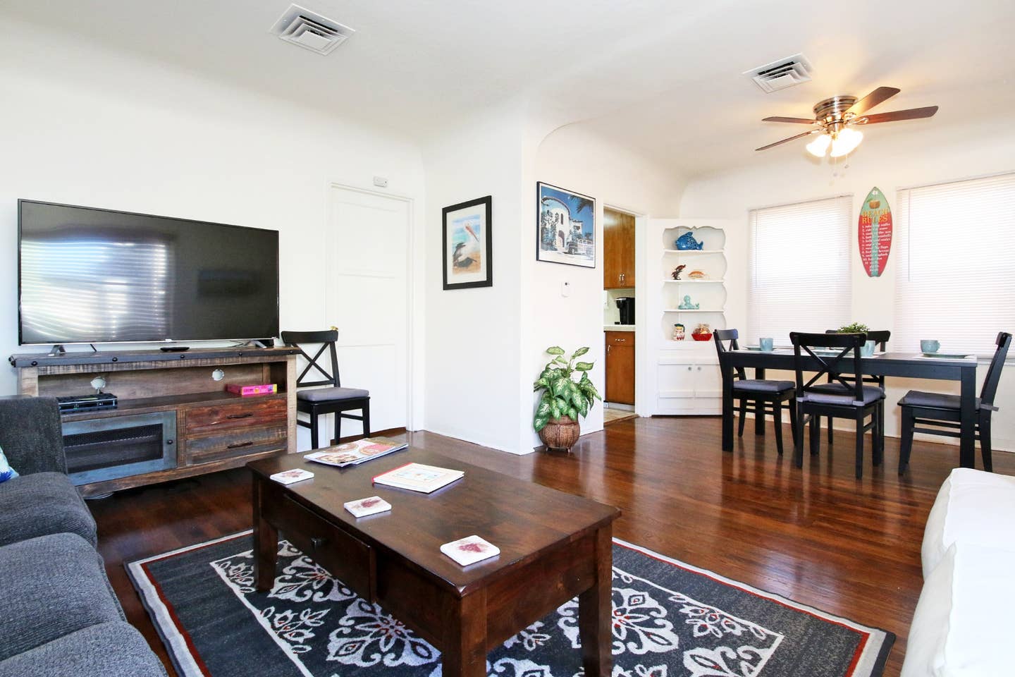 A living room with a couch , table , chairs and a flat screen tv.