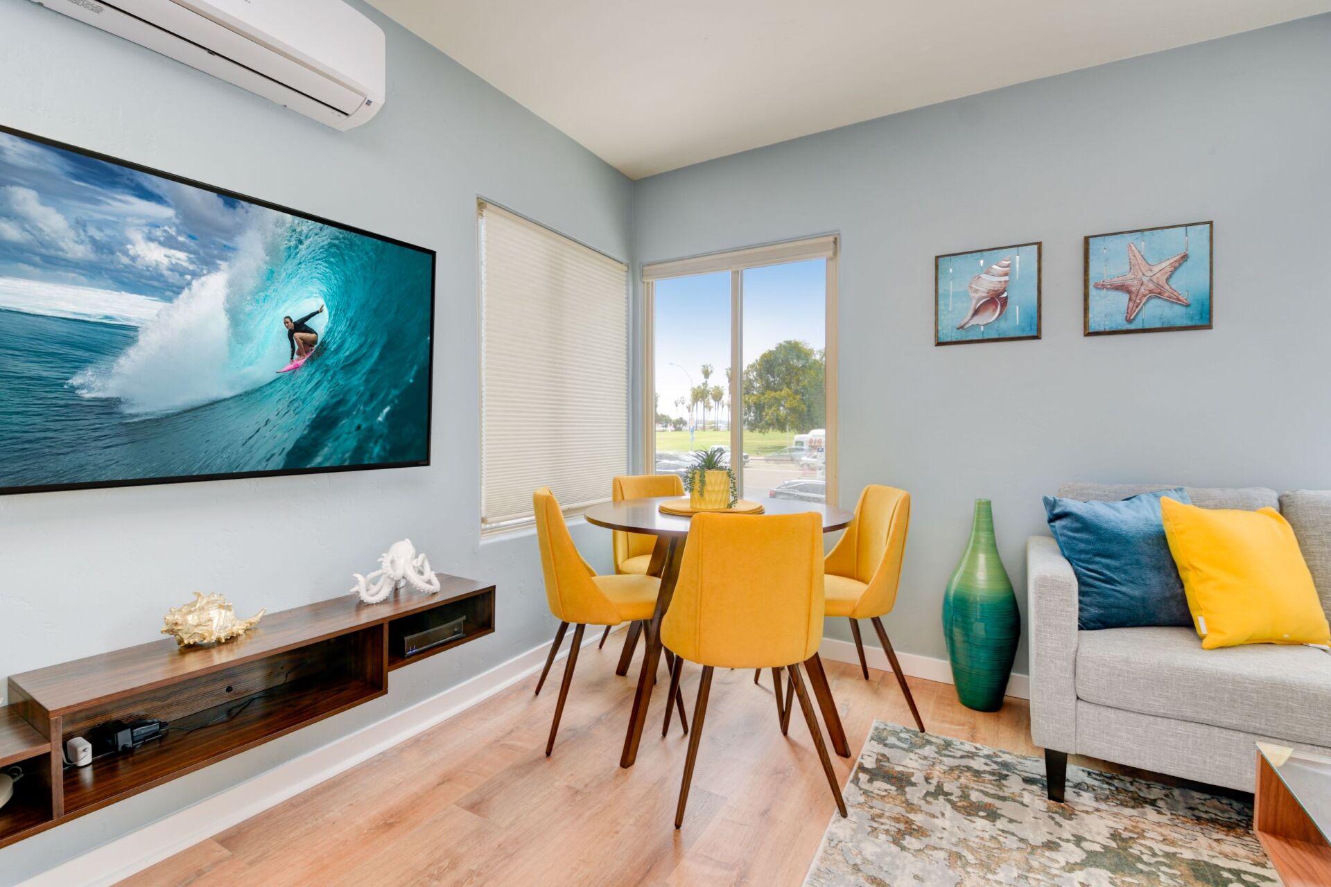 A living room with a couch , table , chairs and a flat screen tv.