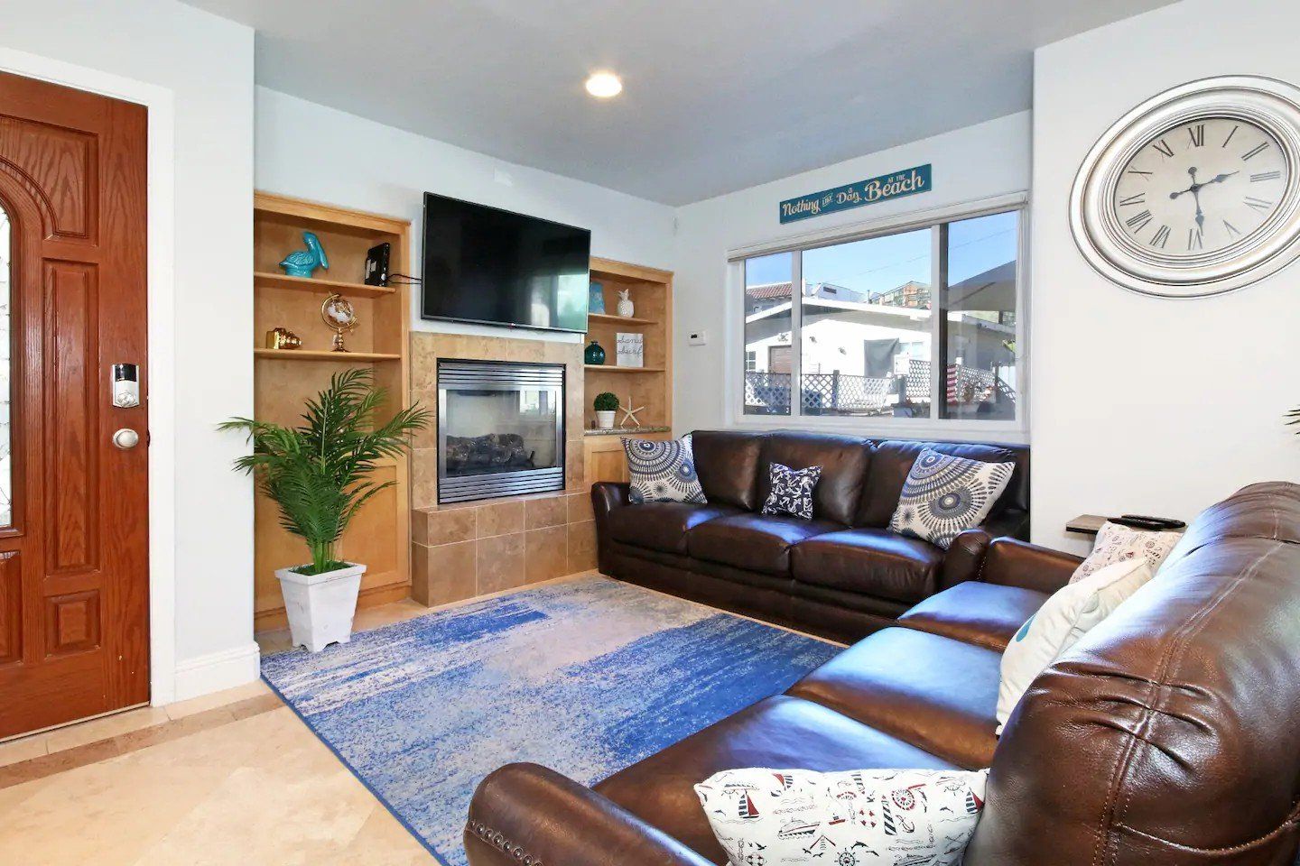 A living room with a couch , chair , television and fireplace.