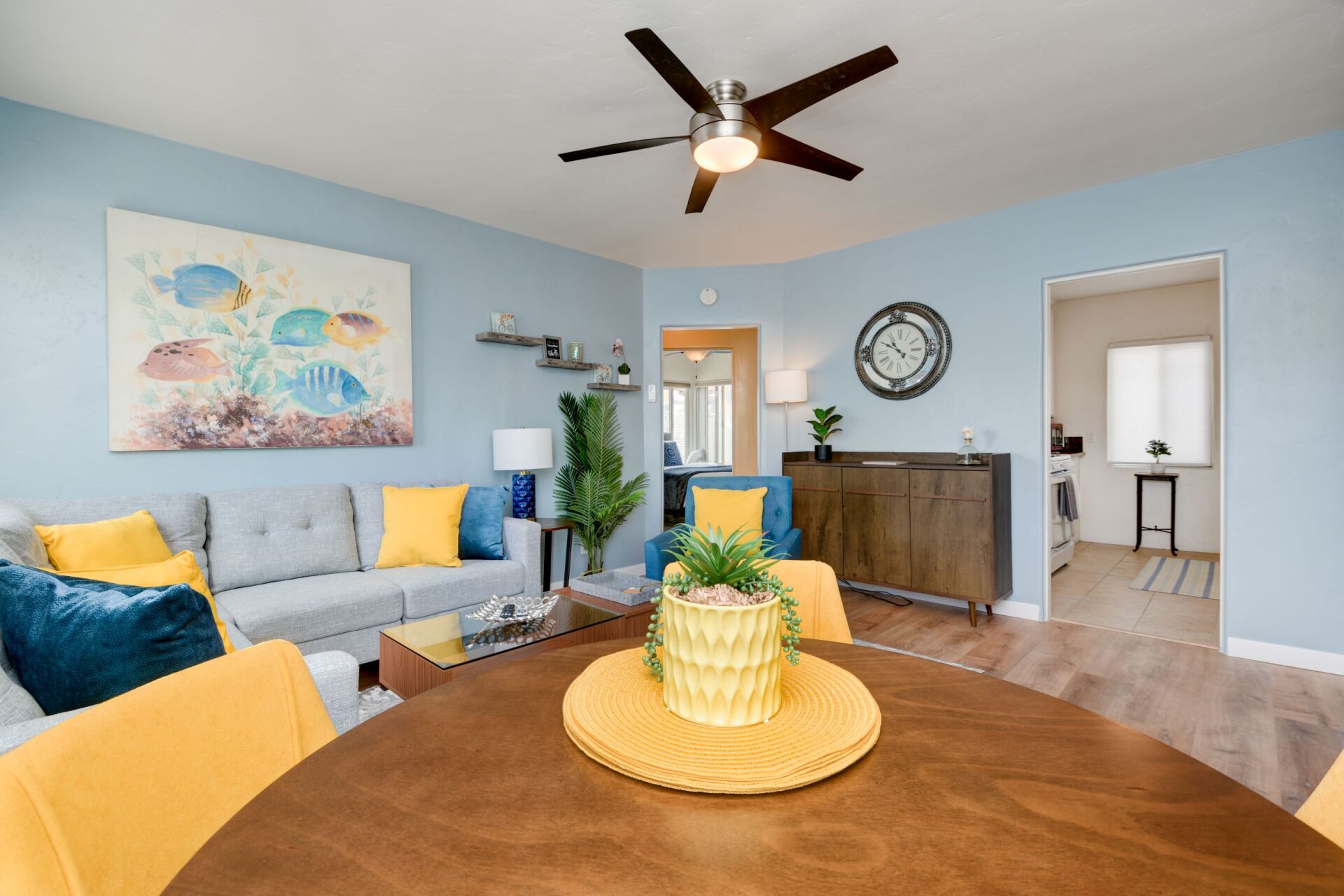 A living room with a round table and a ceiling fan.