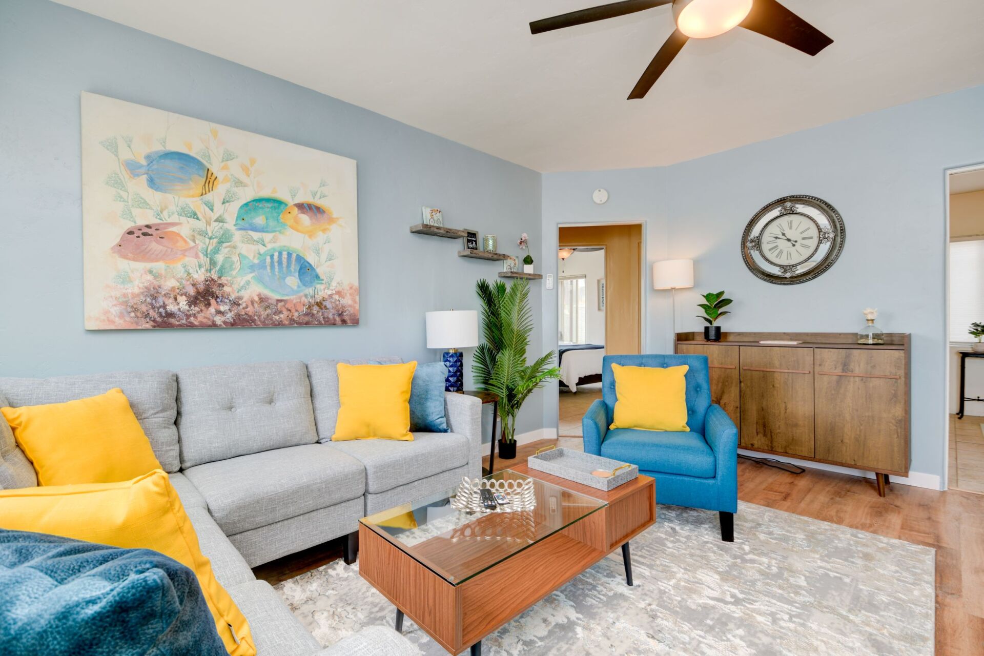 A living room with a couch , chair , coffee table and a ceiling fan.