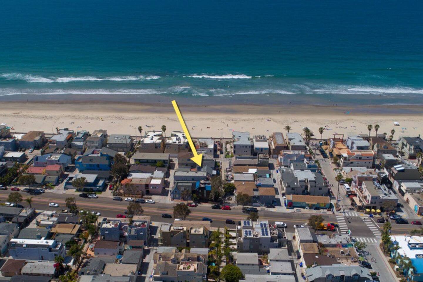 An aerial view of a beach with a yellow arrow pointing to a house.