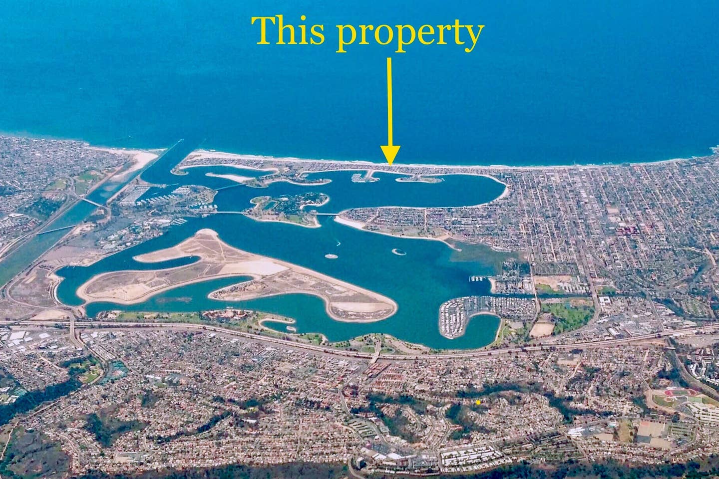 An aerial view of a body of water with a yellow arrow pointing to the property